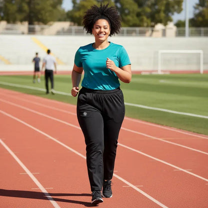 Person running on a track wearing a teal shirt and black pants.