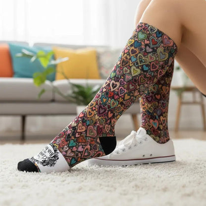 Colorful heart-patterned socks worn with white sneakers in a living room setting.